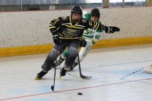Two hockey players competing intensely on the ice rink, focused on the puck during a fast-paced game.