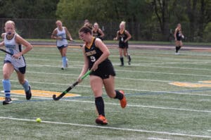 Field hockey players in action during a match on a sunny day.
