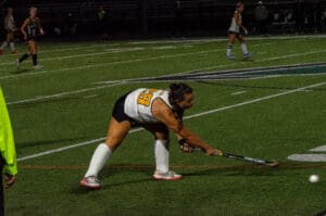 Field hockey player preparing to hit the ball during a night match.