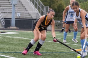Field hockey players competing intensely on the field, focused on the ball during a match.