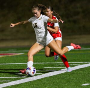 Soccer players in action during a night game, player 15 controlling the ball on the field.