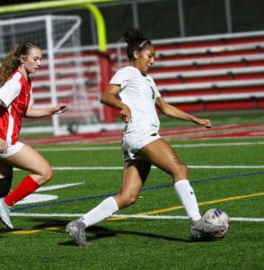 Soccer players in action on the field during a competitive match, focusing on ball control and teamwork.