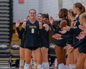 Volleyball player in Tigers uniform high-fives teammates before a game.