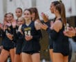 Girls' volleyball team applauding teammate wearing Tigers jersey number 24 in a sports hall.