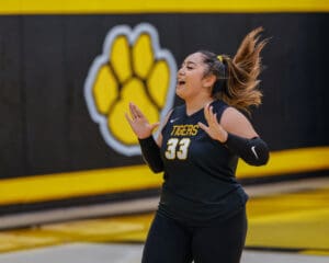 Excited volleyball player in black jersey with Tigers 33 logo celebrates during a match.