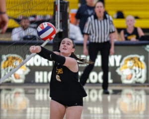 Volleyball player in action, diving to hit the ball during a high school match.
