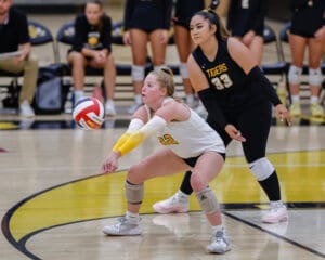 Volleyball players focused in action on the court, preparing for a game-winning move during a competitive match.