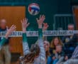Volleyball player spikes ball over net during intense match at Pine-Richland Rams game.