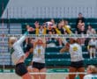 Women's volleyball game action with player spiking ball against blockers at Pine-Richland Rams match.