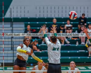 Volleyball player in action, spiking the ball over the net during an indoor match. Pine-Richland Rams competition.