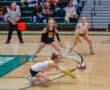 Volleyball player dives to hit the ball during a competitive indoor match.