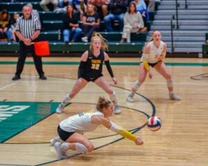 Volleyball player dives to hit the ball during a competitive indoor match.