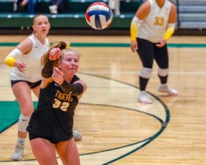 Volleyball player in action, wearing black Tigers jersey, focusing on returning the ball during a match.
