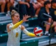 Young female volleyball player prepares to serve during a match, wearing number 8 jersey and yellow arm sleeves.