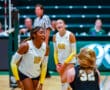 Women's volleyball players celebrate point during a match, wearing white jerseys with numbers 10 and 22.