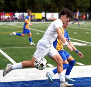 Soccer players in action on the field, one kicking the ball during an intense match.