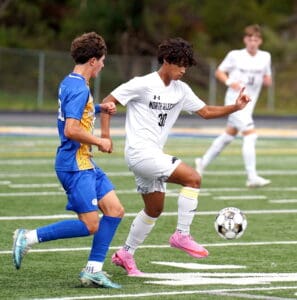 Two soccer players in action on a field, one in blue and one in white, focusing on the ball.