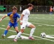 Soccer players competing for ball on lush green field during an intense match.