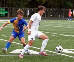 Soccer players competing for ball on lush green field during an intense match.