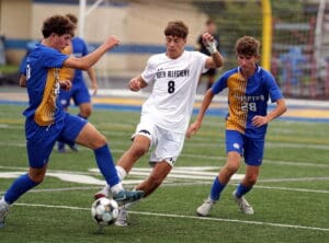 Soccer players in blue and white uniforms clash for the ball on a green field during a competitive match.