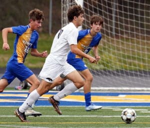 Soccer players in action during a match, focusing on the player in white dribbling past defenders.