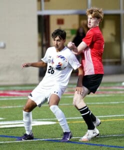 Two soccer players competing for the ball during a match on a green field.
