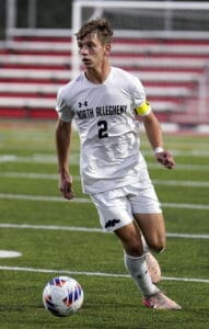 Soccer player in white North Allegheny uniform dribbles on field during a match.