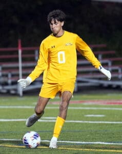 Soccer player in yellow jersey kicking a ball on a field.