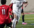 Soccer match action with player in white from North Allegheny dribbling past opponents on field.