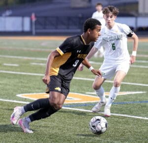 Soccer players in action on the field, one in black jersey and one in white, competing for the ball.