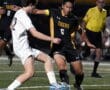 Soccer players compete for the ball during a night match, with referee observing action on the field.