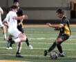 Soccer players compete intensely for the ball during a night match on a grass field.