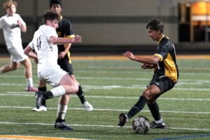 Soccer players compete intensely for the ball during a night match on a grass field.