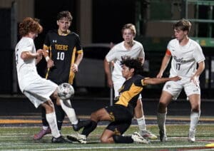 Soccer players in action during a match, competing intensely for the ball on a sports field at night.