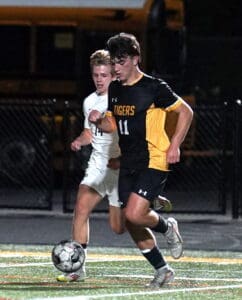 Soccer players in action during a night match, player in yellow jersey controlling the ball with close opponent.