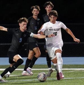 Soccer match action with players in black and white jerseys competing for the ball on the field.