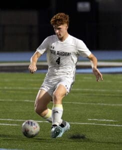 Soccer player in white uniform with North Allegheny dribbling on field, focused on the ball during a match.