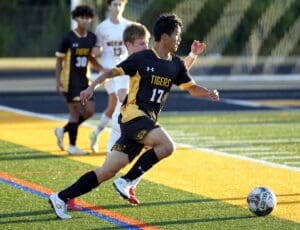 Soccer player in black number 17 jersey running for ball on field during match, action shot.
