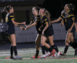 Soccer players in black jerseys celebrate a goal on the field, displaying teamwork and sportsmanship.