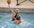 Water polo player prepares to shoot the ball in a competitive match, showcasing athleticism and focus in the pool.