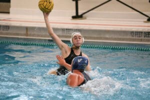 Water polo player prepares to shoot the ball in a competitive match, showcasing athleticism and focus in the pool.