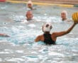 Water polo player preparing to pass the ball during a competitive match in a pool.