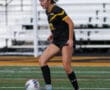 Soccer player in black and yellow uniform controlling the ball on the field.