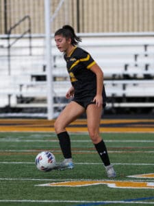 Soccer player in black and yellow uniform controlling the ball on the field.