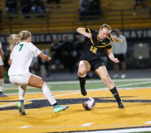 Soccer players in action on the field during a nighttime match, focusing on control and skill with the ball.