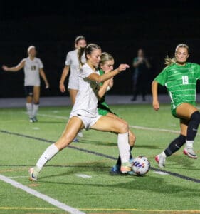 Soccer players in action on the field during a night match, tackling and competing for the ball.