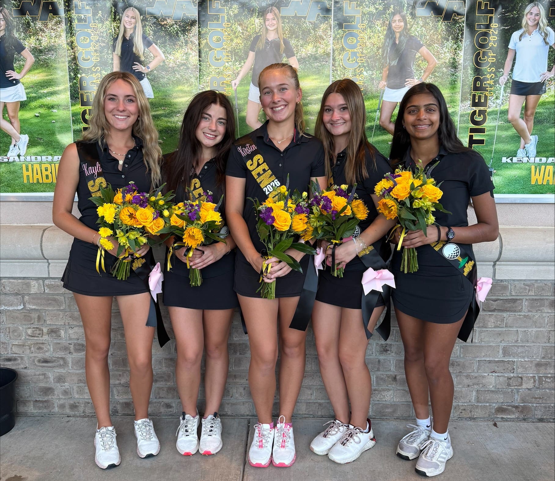 Golf team seniors celebrating with flowers in front of posters, wearing black outfits and sashes.