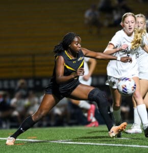 Female soccer players in action, competing for the ball during a night match on a professional field.