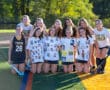 High school field hockey team posing on the field in custom shirts, celebrating teamwork and sportsmanship.