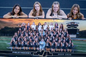 High school field hockey team with a banner, four players smiling, North Allegheny 2025-2026 season at Wright Field.